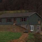 a house is sitting on top of a hill in the middle of a field .
