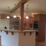 A kitchen with wooden cabinets , a stove , a microwave , and a bar.