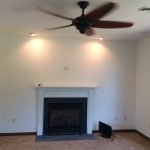 A living room with a fireplace and a ceiling fan.