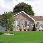 A large brick house with a lush green lawn in front of it.
